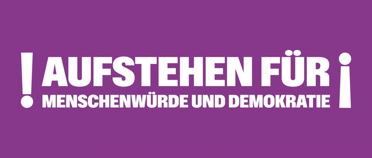 Auf lila Hintergrund steht Aufstehen für Menschenwürde und Demokratie; umrahmt von Ausrufezeichen