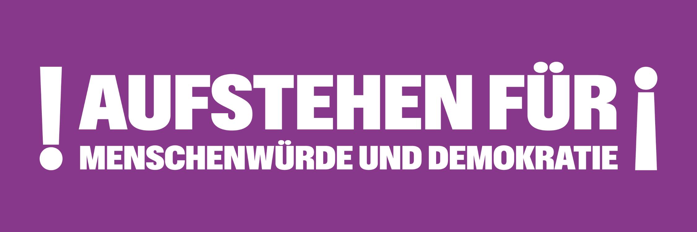 Auf einem lila Banner steht 'Aufstehen für Menschnwürde und Demokratie', rechts und links mit Ausrufezeichen umrahmt