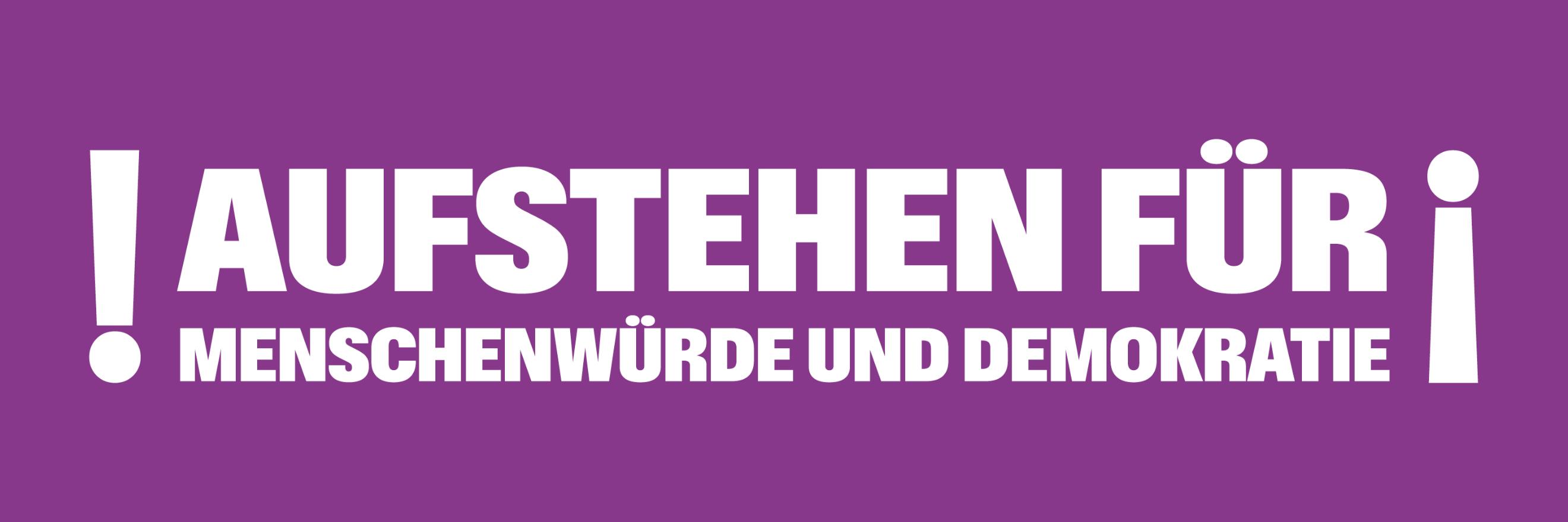 Auf einem lila Banner steht 'Aufstehen für Menschnwürde und Demokratie', rechts und links mit Ausrufezeichen umrahmt