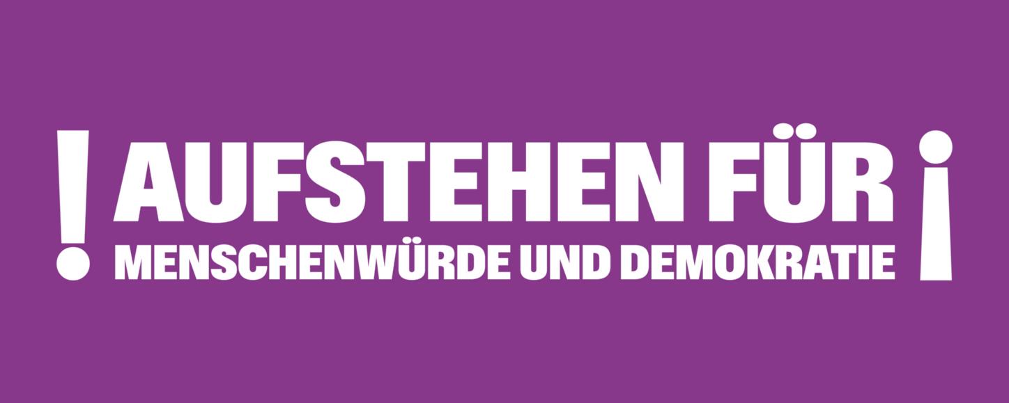 Auf einem lila Banner steht 'Aufstehen für Menschnwürde und Demokratie', rechts und links mit Ausrufezeichen umrahmt