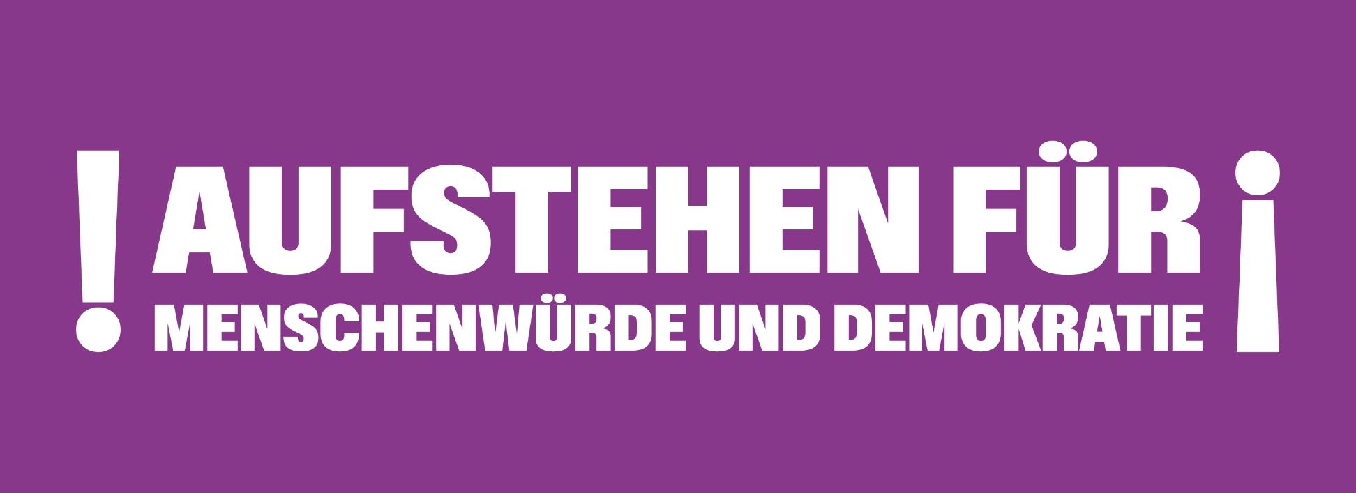 Auf einem lila Banner steht 'Aufstehen für Menschnwürde und Demokratie', rechts und links mit Ausrufezeichen umrahmt