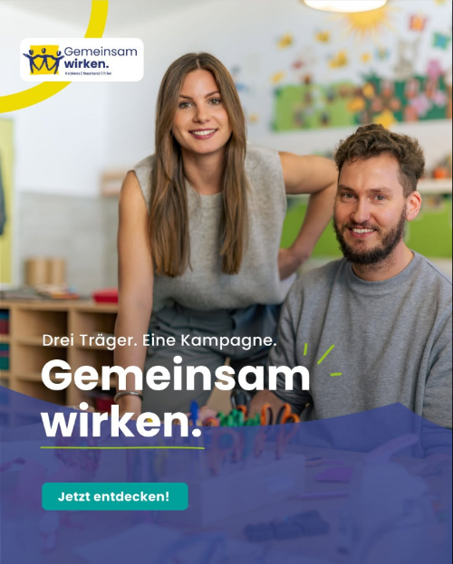 Kampagnenmotiv (c) Gemeinsam wirken Eine Frau und ein Mann stehen in einem Kita-Raum und lächeln in die Kamera