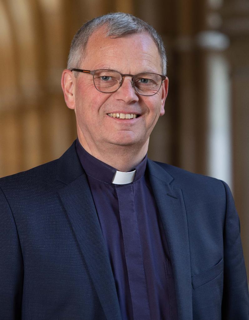 Hier ist Generalvikar Ulrich Graf von Plettenberg  lächelnd im Kreuzgang zusehen.