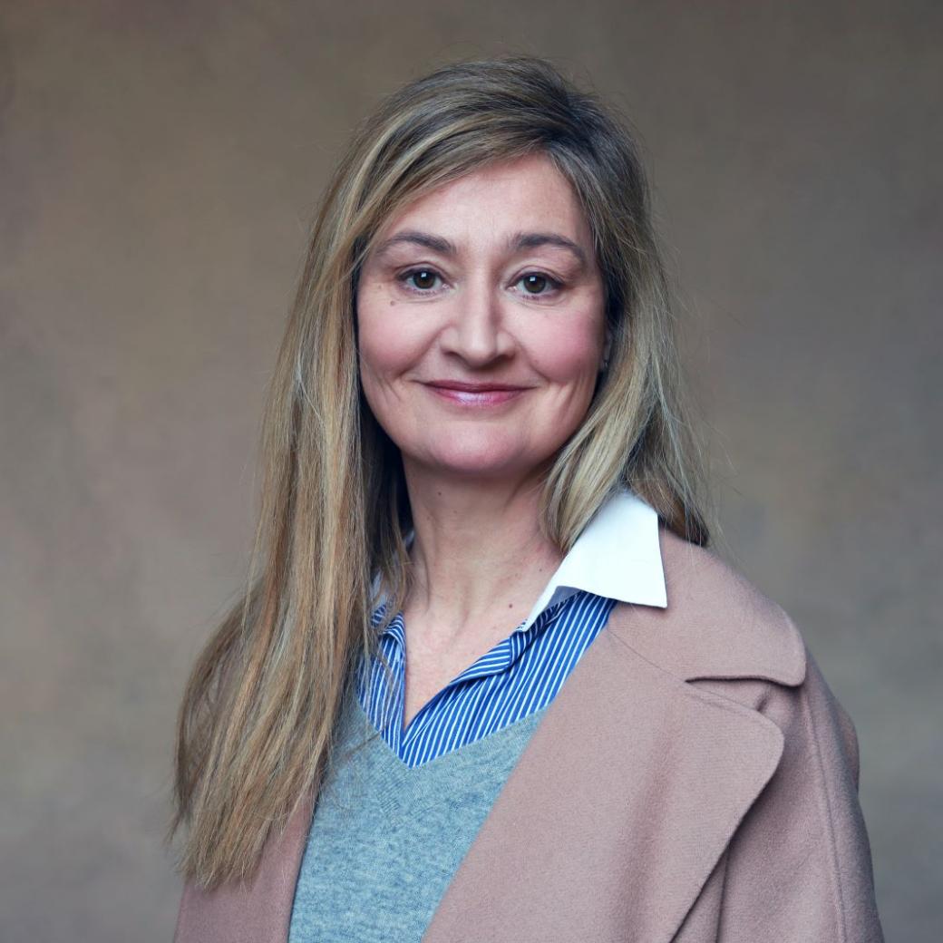 Man sieht eine Frau mit langen blonden Haaren, die in die Kamera lächelt