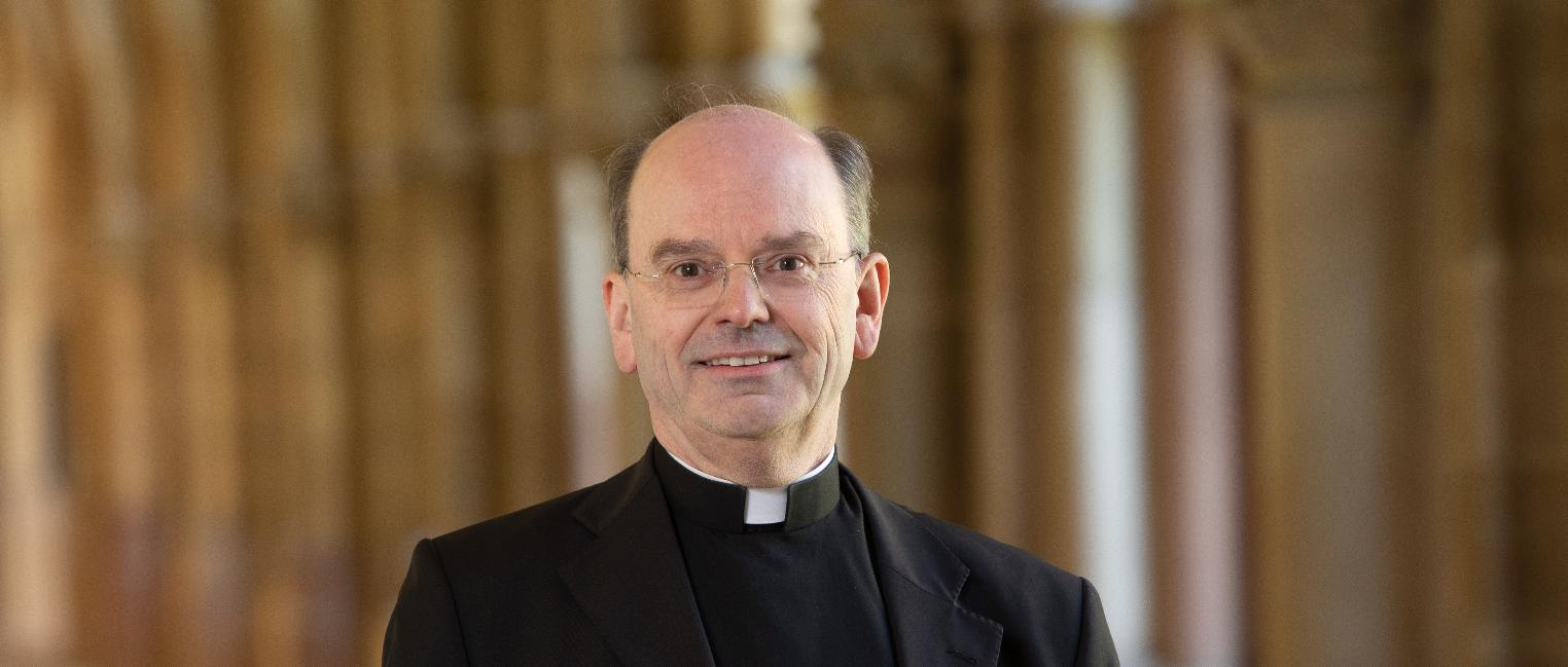 Hier ist Weihbischof Brahm lächelnd im Kreuzgang zusehen.