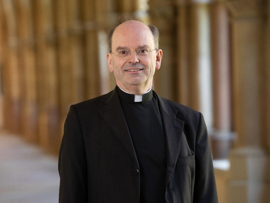 Hier ist Weihbischof Brahm lächelnd im Kreuzgang zusehen.