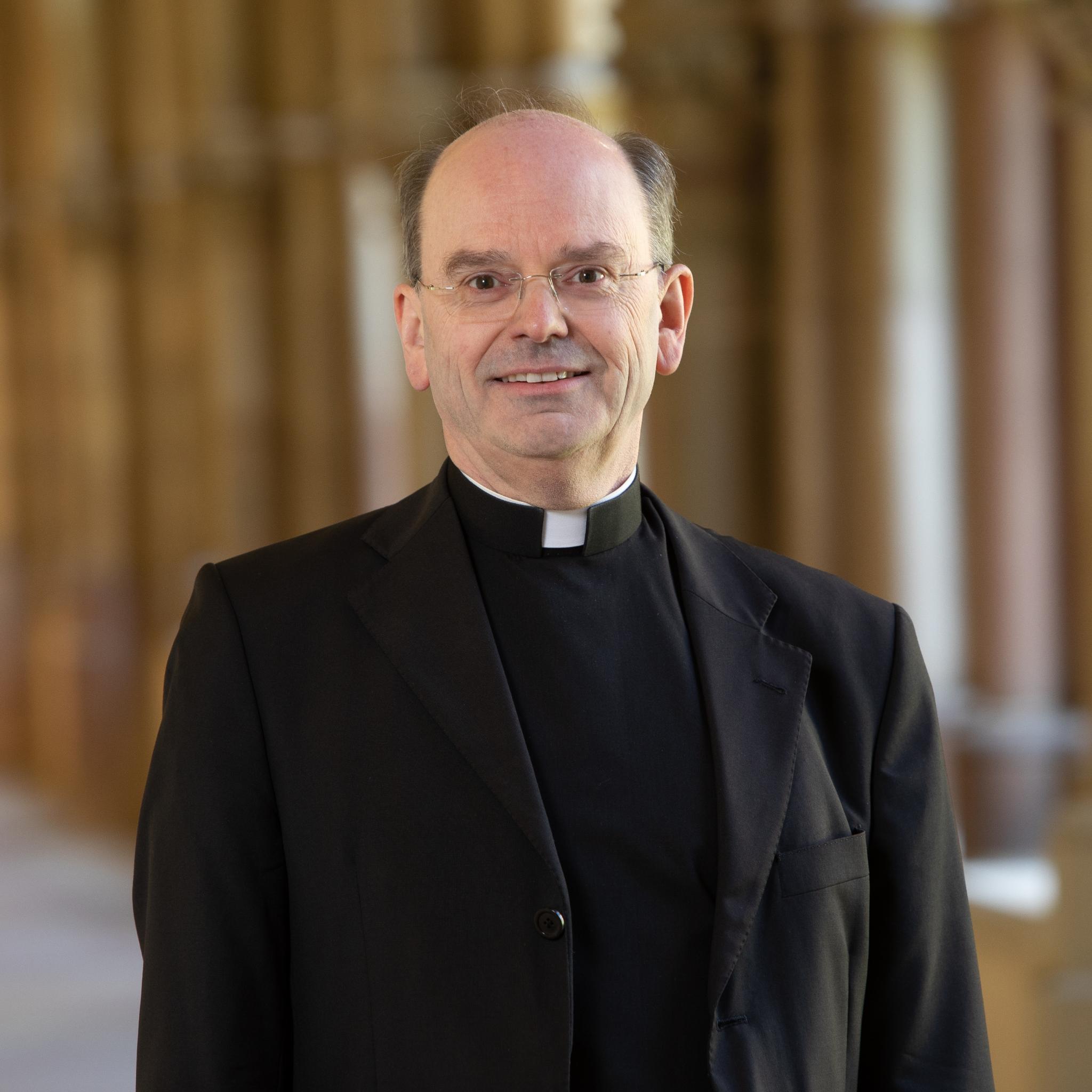 Hier ist Weihbischof Brahm lächelnd im Kreuzgang zusehen.