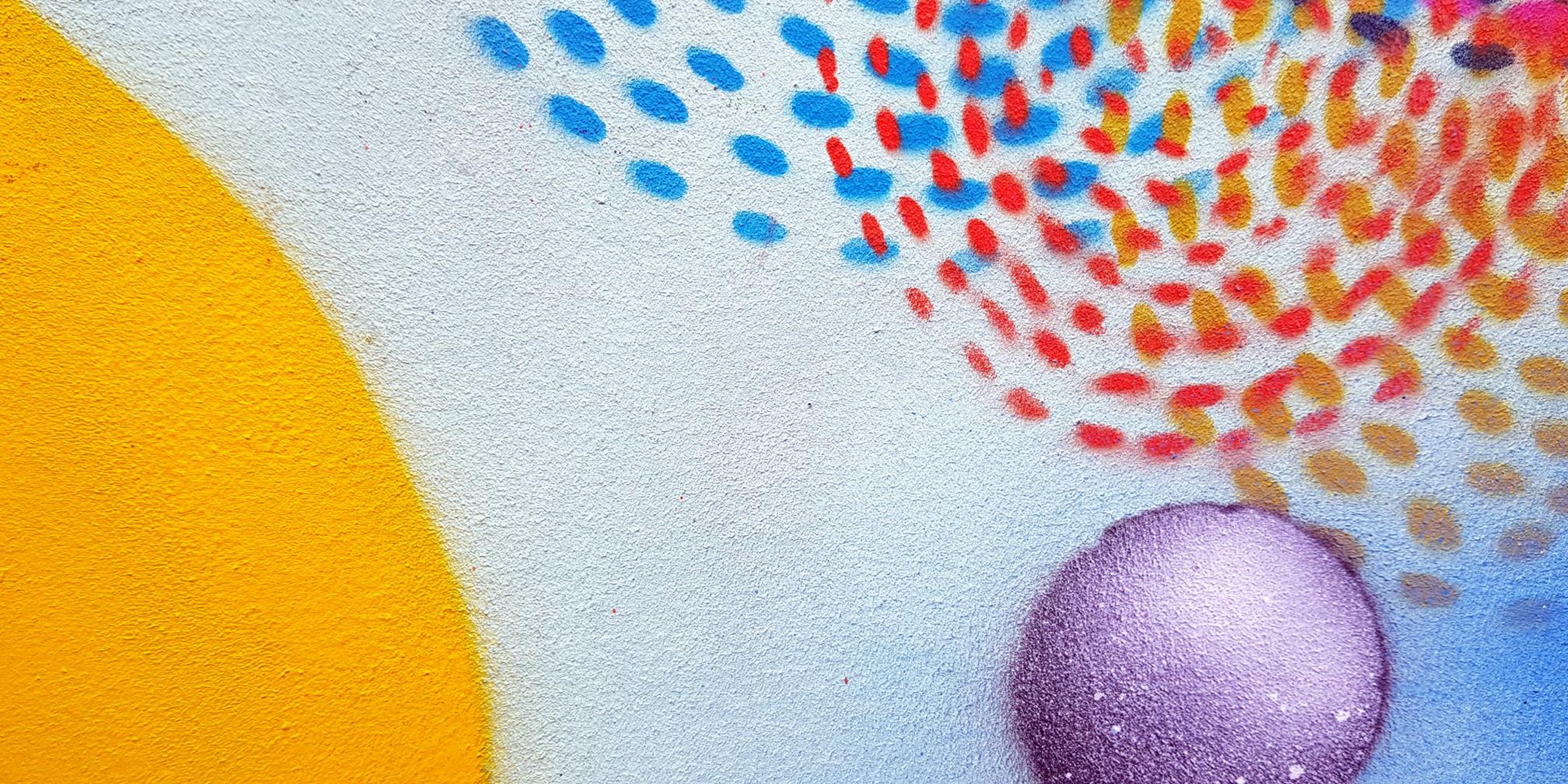 Man sieht Graffiti in Form von Punkten und Kreisen an einer Wand
