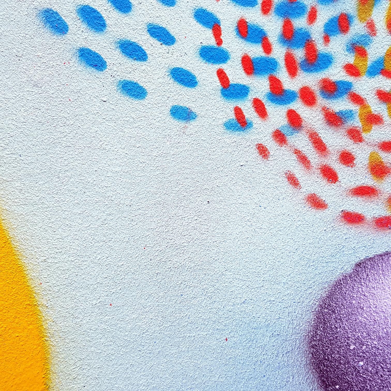 Man sieht Graffiti in Form von Punkten und Kreisen an einer Wand