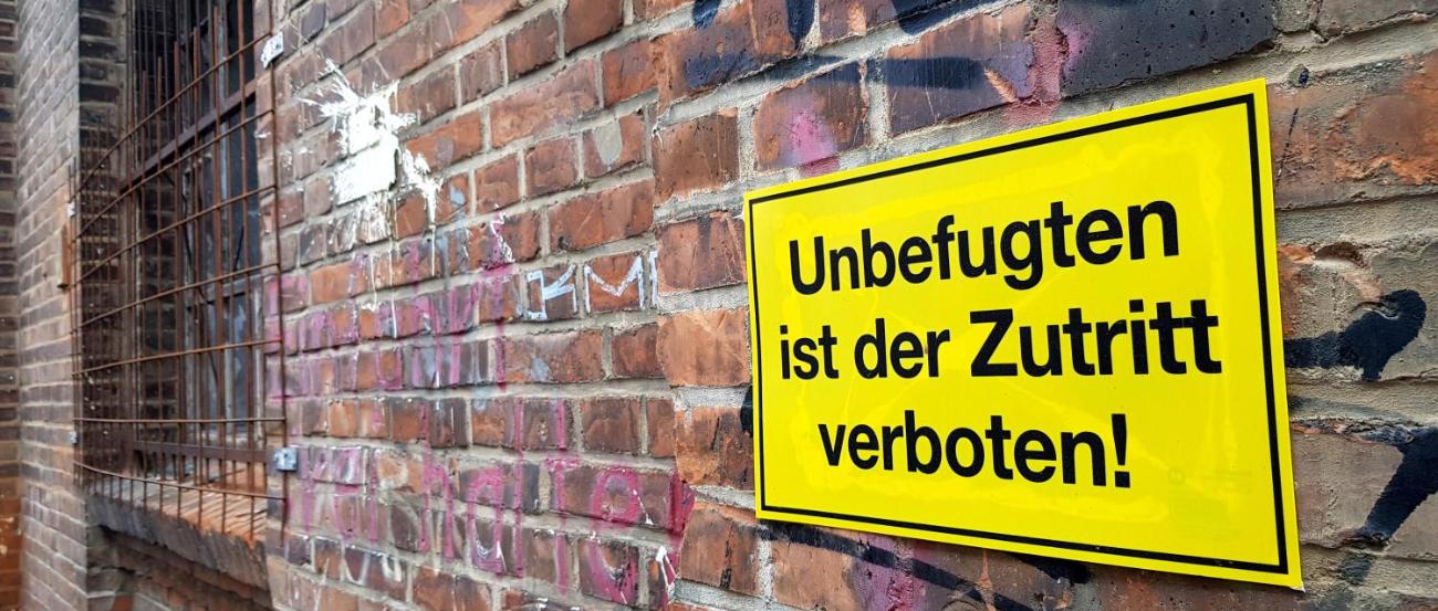 Man sieht eine Mauer mit einem Warnschild: Unbefugten ist der Zutritt verboten.