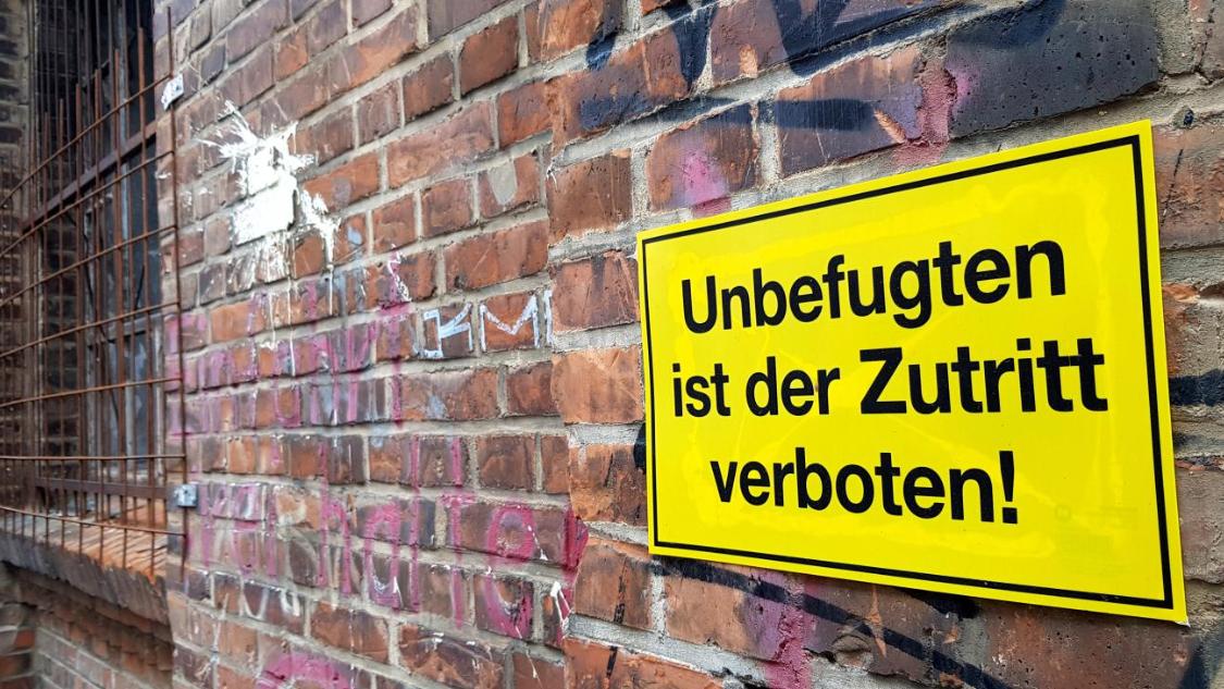 Man sieht eine Mauer mit einem Warnschild: Unbefugten ist der Zutritt verboten.