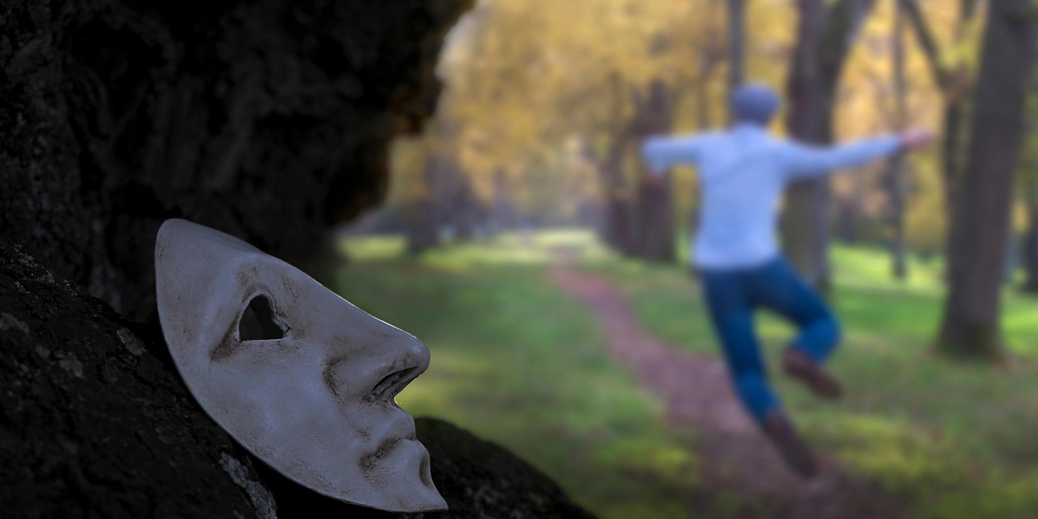 Man sieht links auf einem Felsen eine weiße Karnevalsmaske liegen. Im Hintergrund unscharf hüpft ein Mann vor Freude in die Höhe