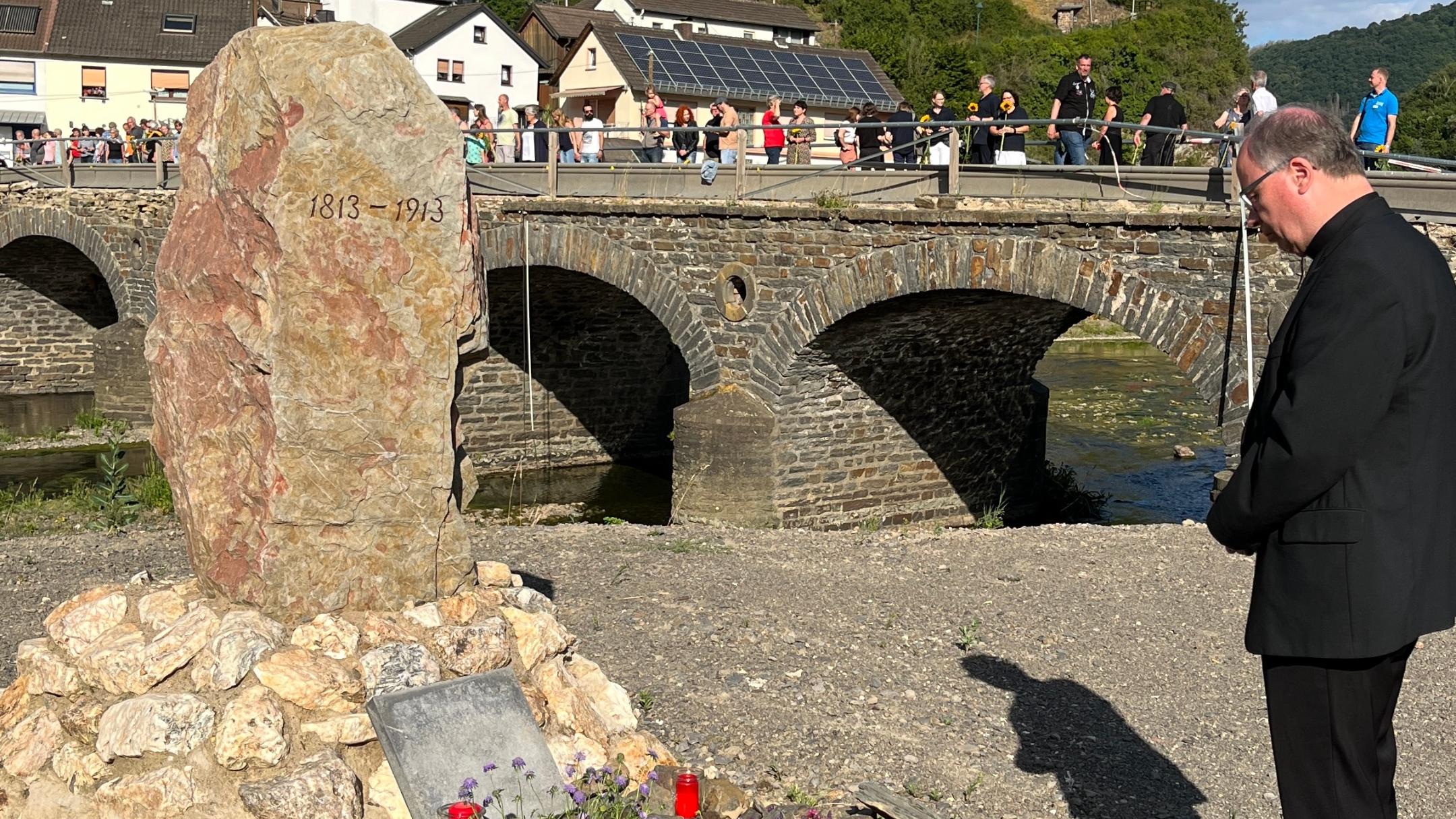 Bischof Ackermann steht vor einem Grabstein und betet