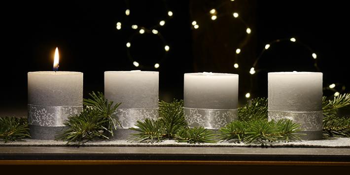 1. Advent (c) Christina Libeaux An einem Adventsgesteck brennt eine Kerze