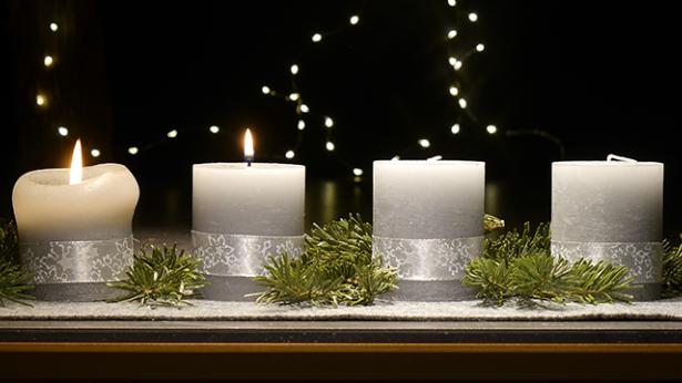 An einem Adventsgesteck brennen zwei Kerzen
