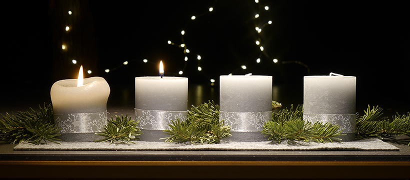 An einem Adventsgesteck brennen zwei Kerzen