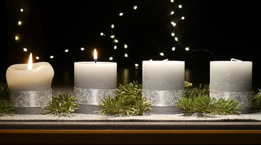 An einem Adventsgesteck brennen zwei Kerzen