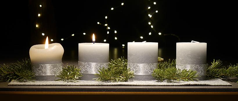 An einem Adventsgesteck brennen zwei Kerzen