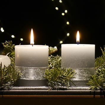 An einem Adventsgesteck brennen drei Kerzen (c) Christina Libeaux An einem Adventsgesteck brennen drei Kerzen