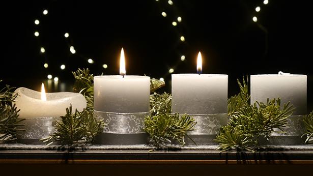 An einem Adventsgesteck brennen drei Kerzen
