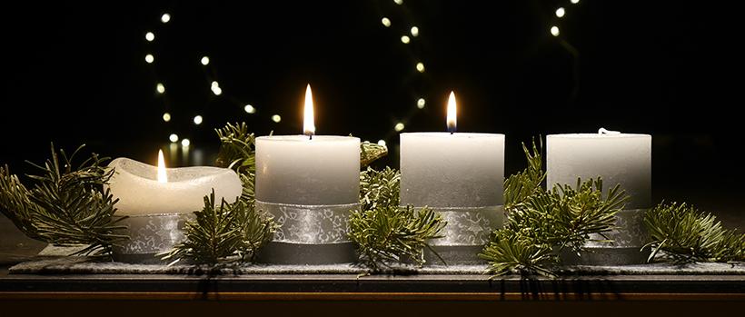 An einem Adventsgesteck brennen drei Kerzen