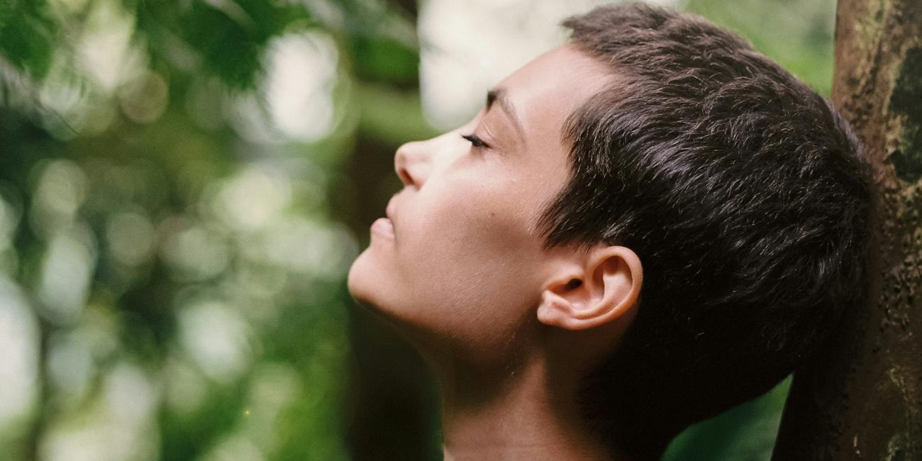 Atem holen (c) Motoki Tonn auf unsplash.com Eine Frau steht im Wald an einen Baum gelehnt und atmet tief ein