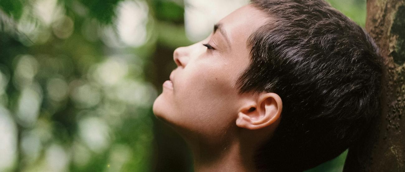 Atem holen (c) Motoki Tonn auf unsplash.com Eine Frau steht im Wald an einen Baum gelehnt und atmet tief ein