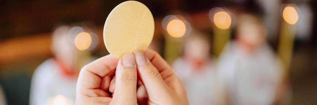 Eucharistie (c) Besim Mazhiqi/ Erzbistum Paderborn Zwei Hände halten die Hostie in die Höhe.