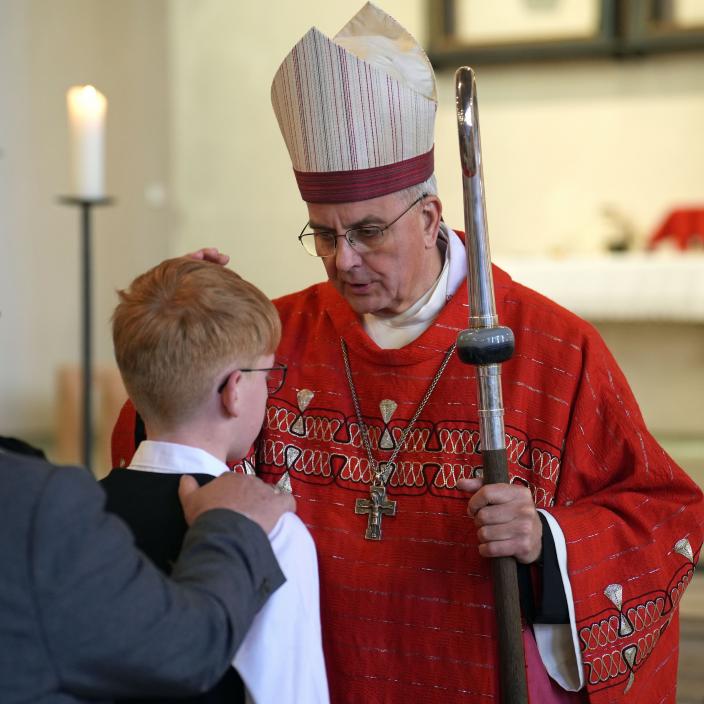 Weihbischof Peters legt einem jungen Menschen die Hand auf den Kopf.