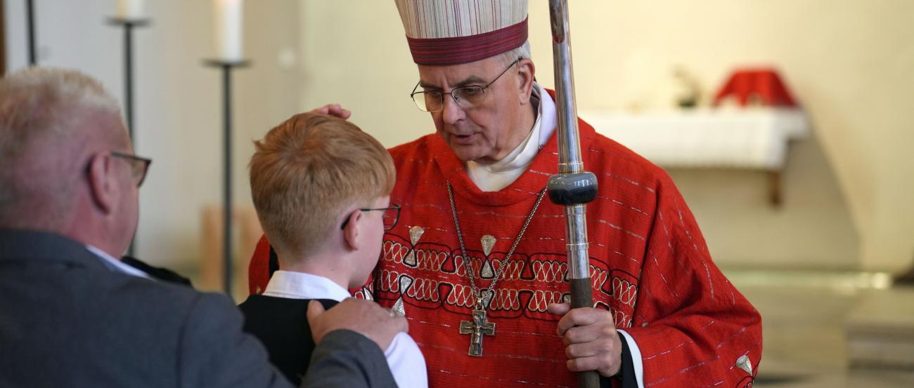 Weihbischof Peters legt einem jungen Menschen die Hand auf den Kopf.