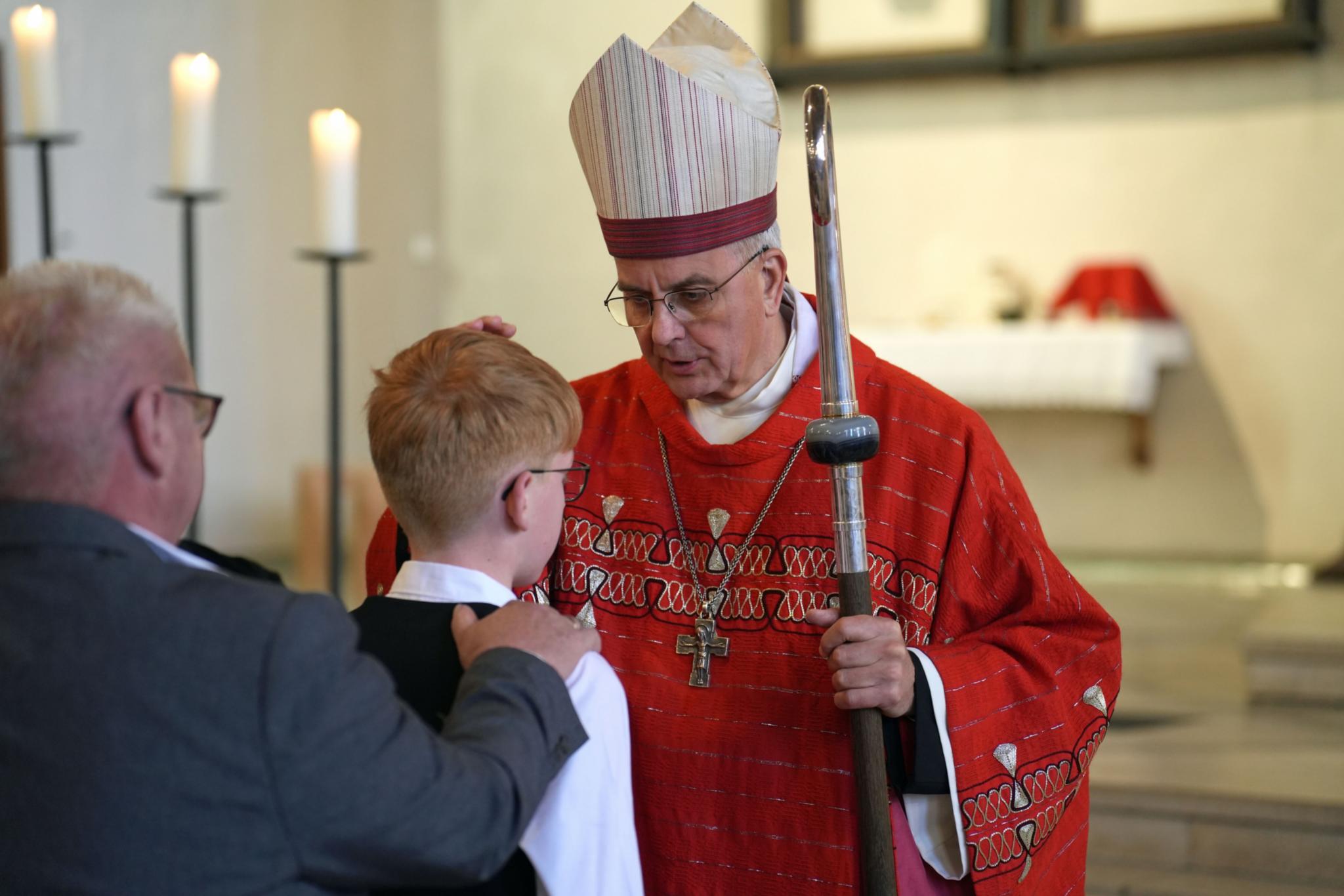 Weihbischof Peters legt einem jungen Menschen die Hand auf den Kopf.