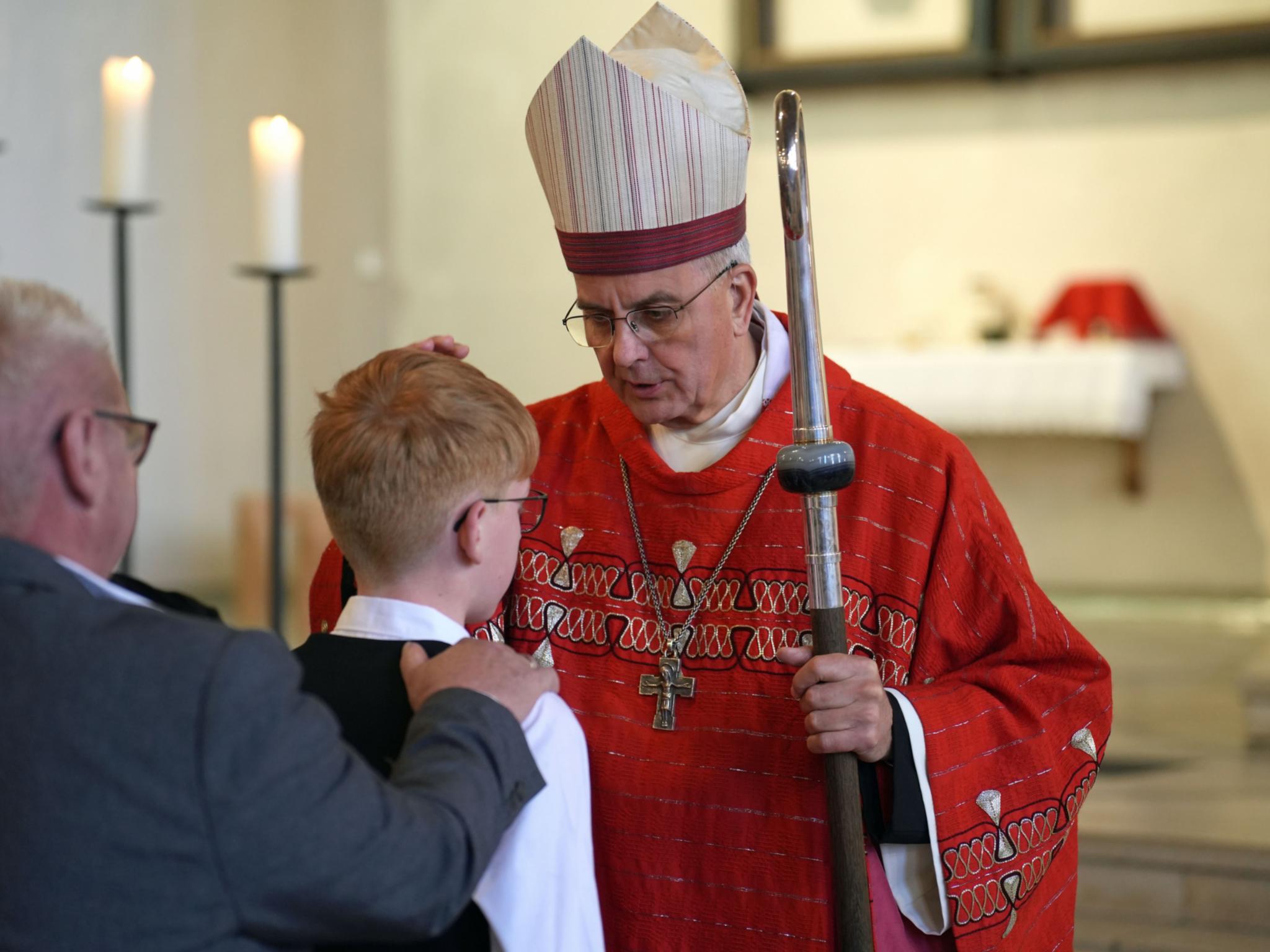 Weihbischof Peters legt einem jungen Menschen die Hand auf den Kopf.