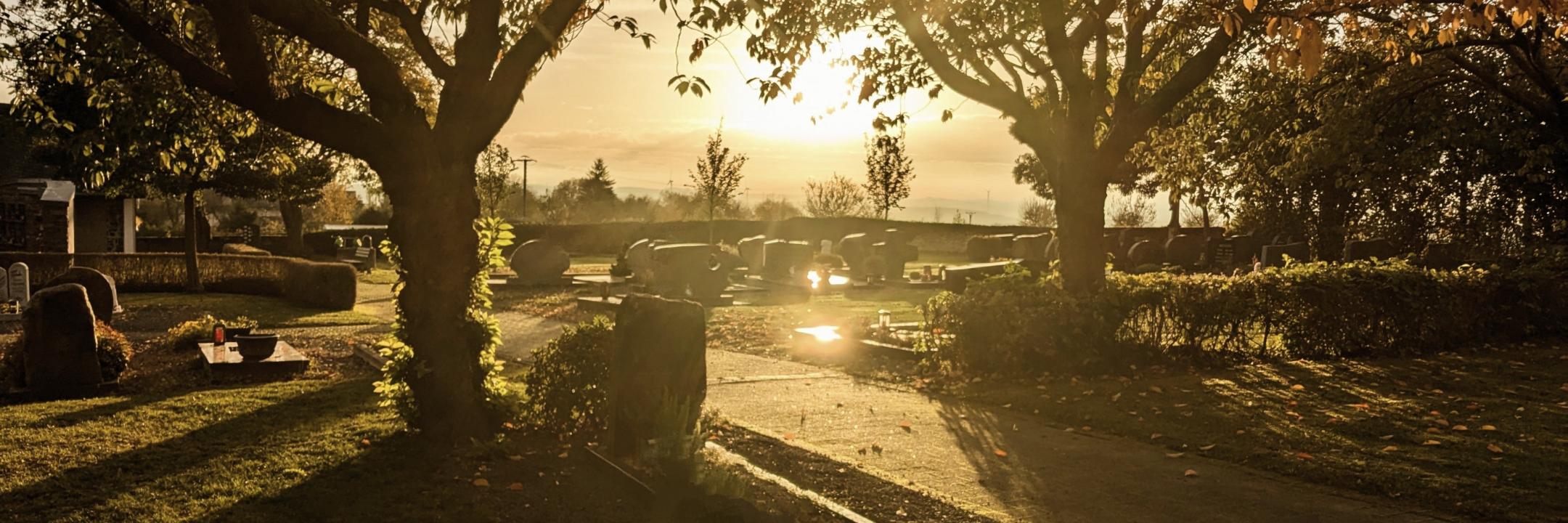 Friedhof bei untergehender Sonne und herbstlicher Stimmung