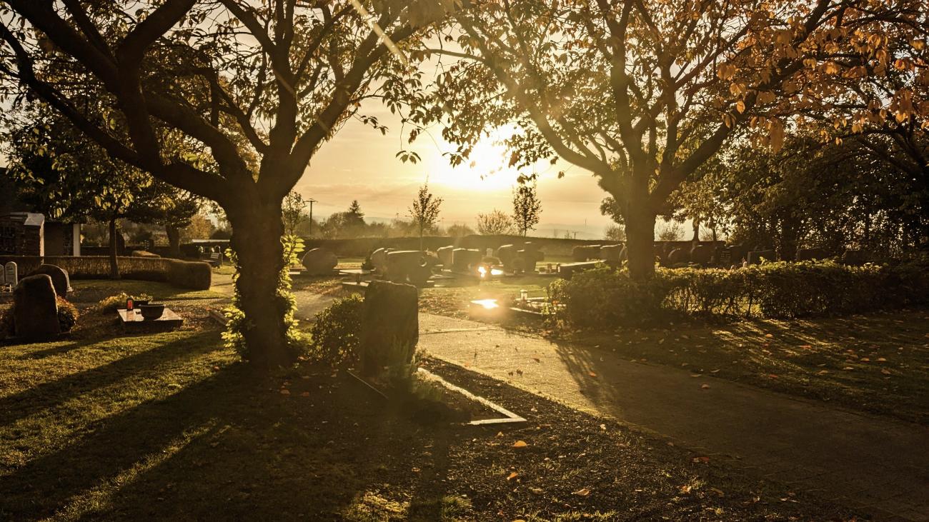 Friedhof bei untergehender Sonne und herbstlicher Stimmung