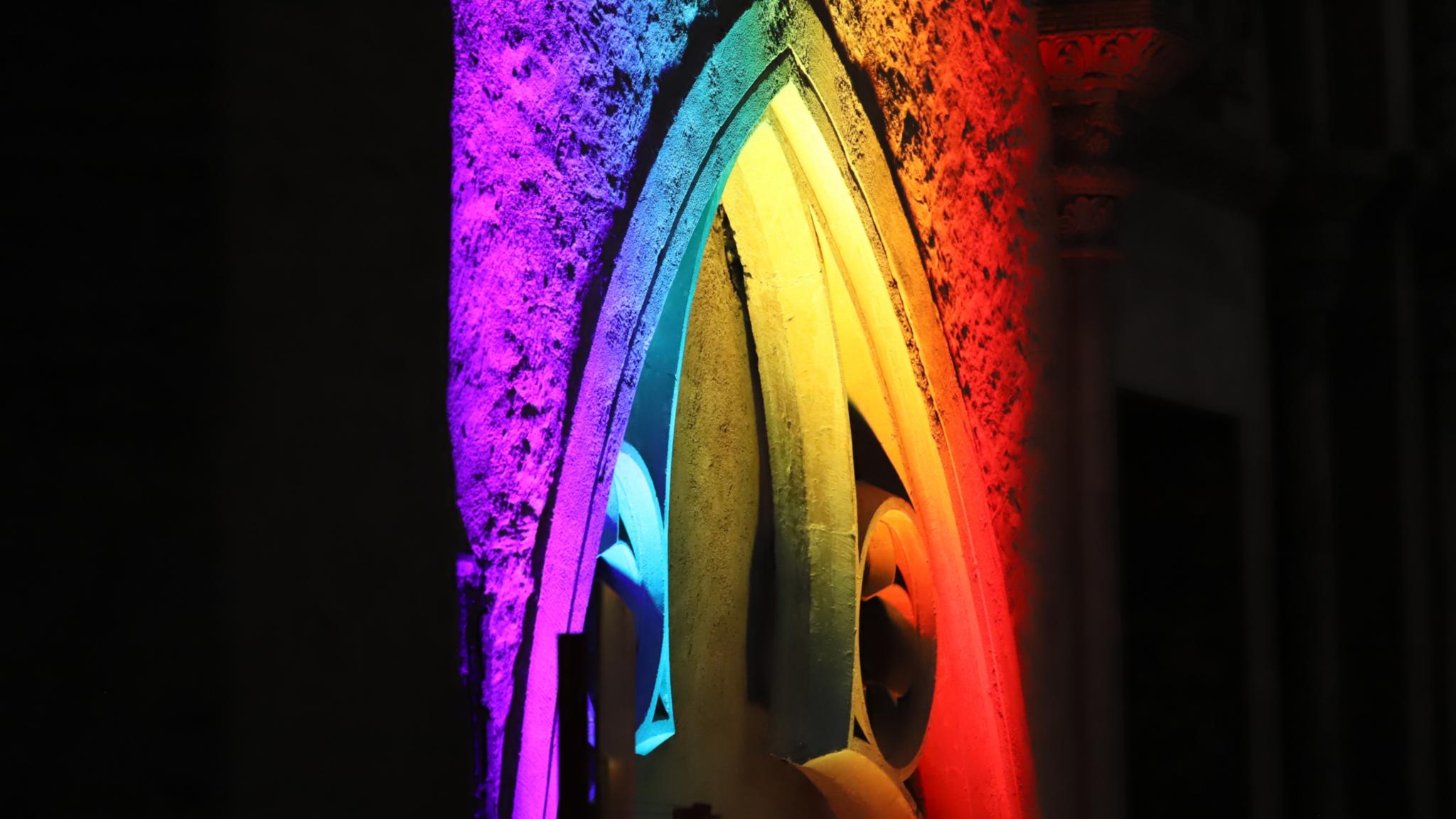 Ein Kirchenfenster ist mit bunten Lichtern bestrahlt