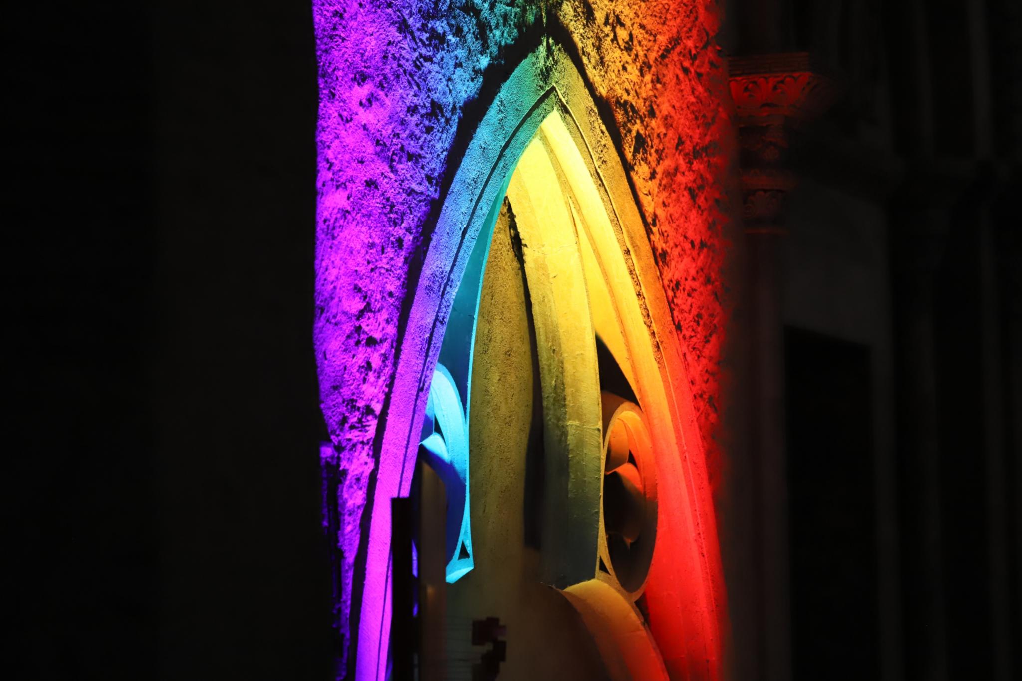 Ein Kirchenfenster ist mit bunten Lichtern bestrahlt