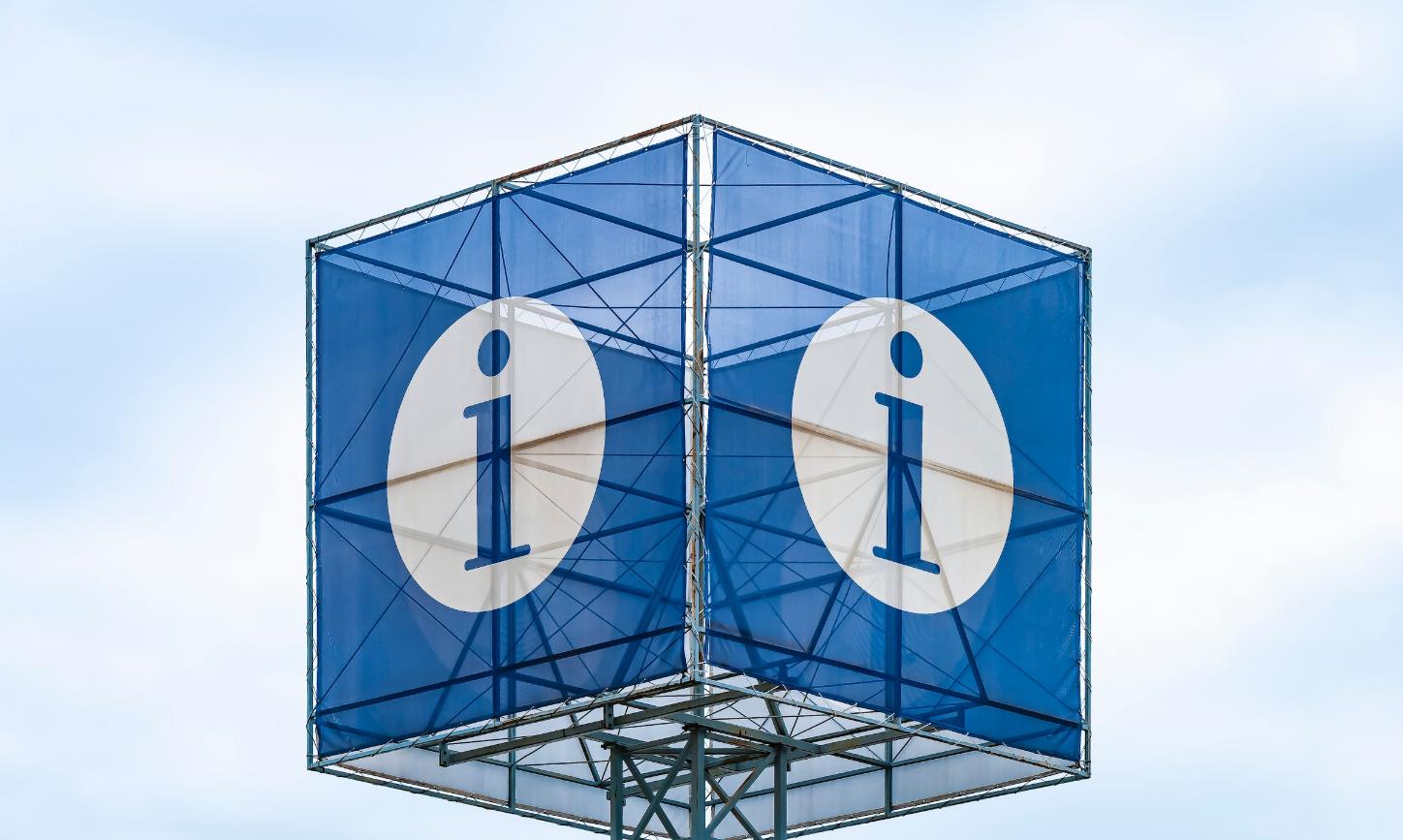 Man sieht einen blauen Kubus auf einem Mast. Auf jeder Seite ist ein weißer Kreis mit einem blauen i in der Mitte zu sehen