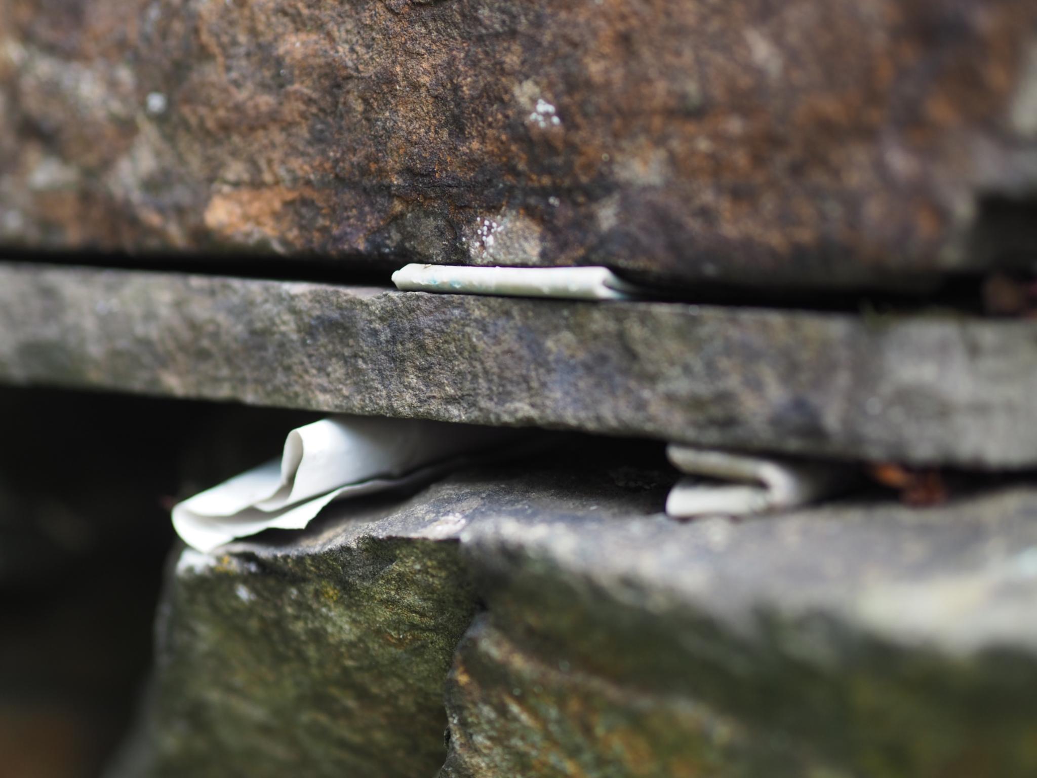 Kleine Zettel stecken zwischen Steinen