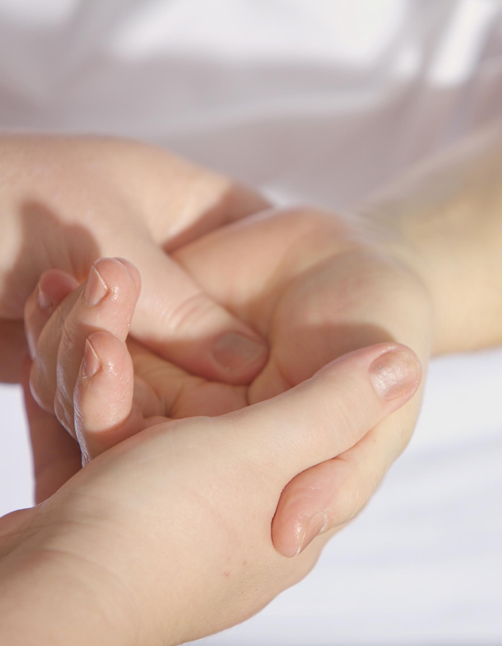 Nahaufnahme zweier Hände, die eine weitere Hand liebevoll umfängt und salbt