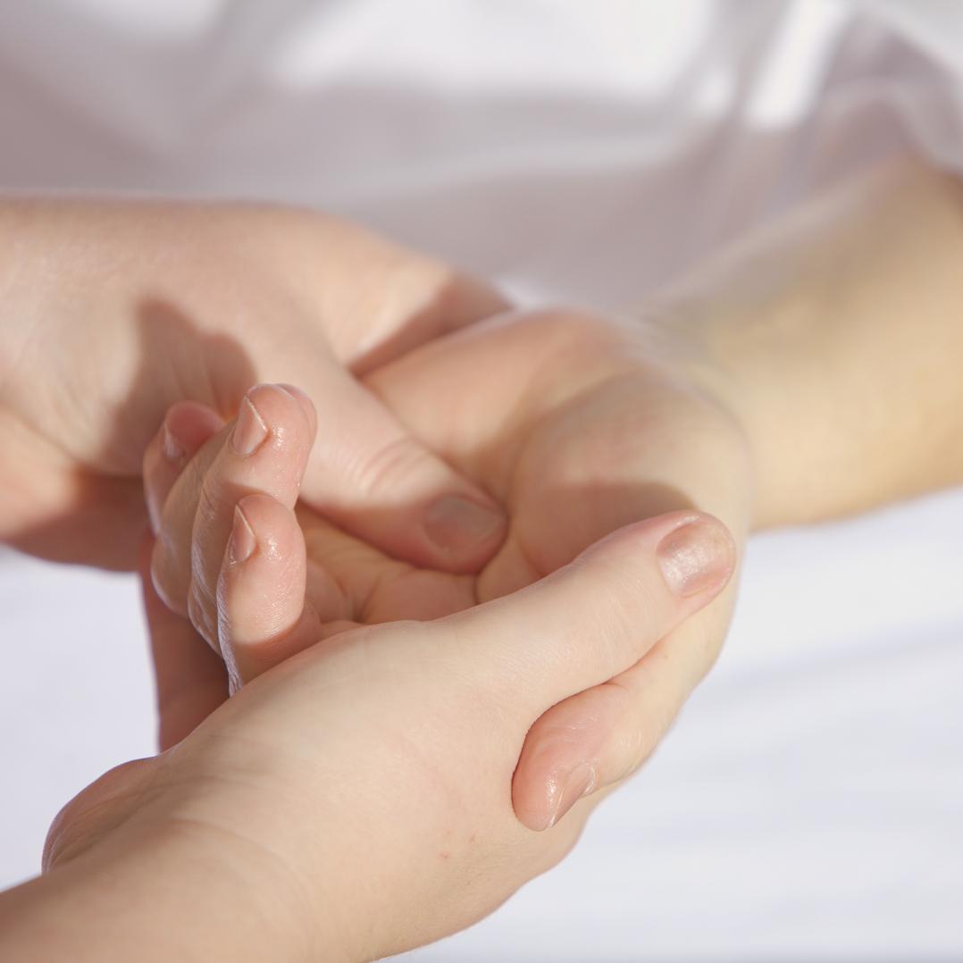 Nahaufnahme zweier Hände, die eine weitere Hand liebevoll umfängt und salbt