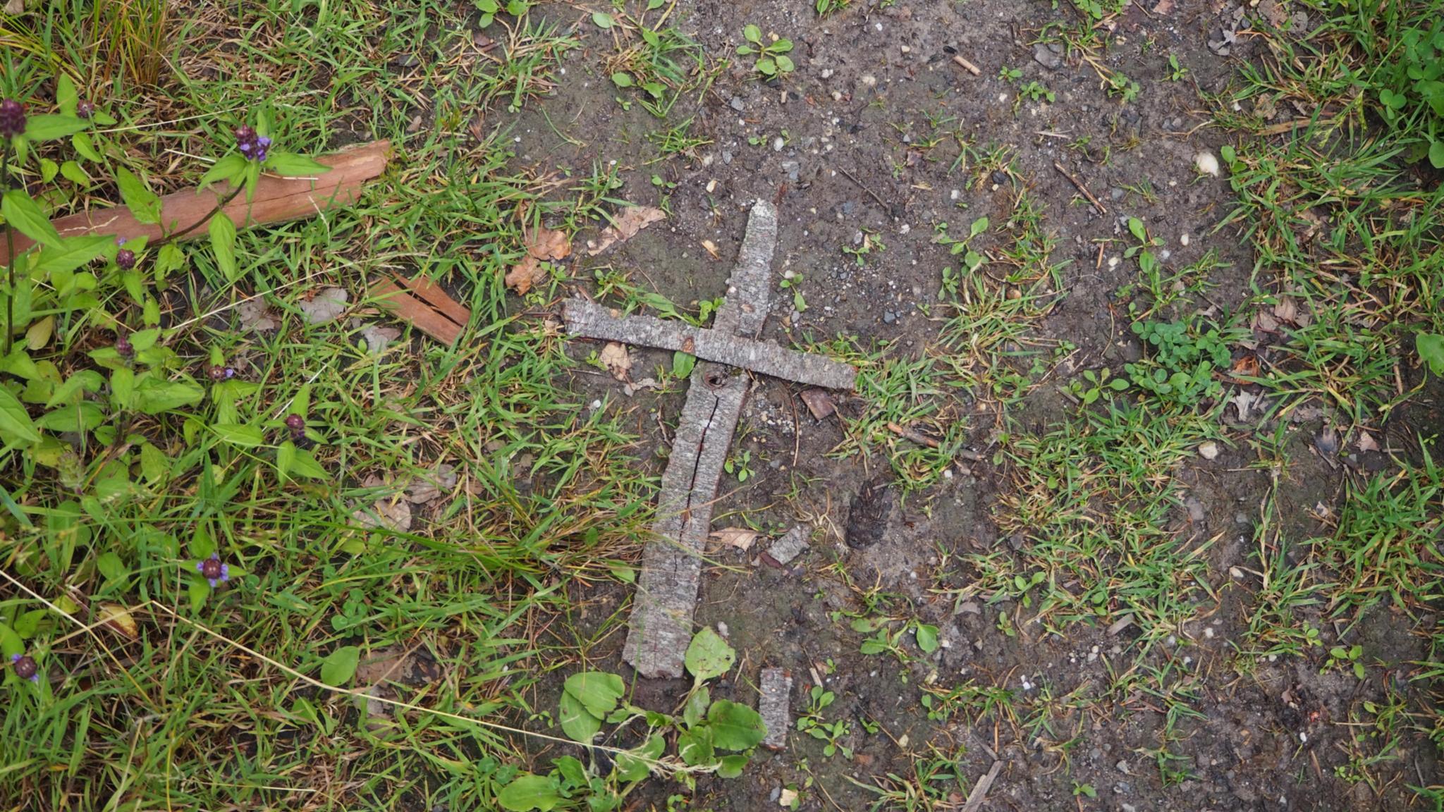 Auf Waldboden liegt ein aus Rinde geformtes Kreuz