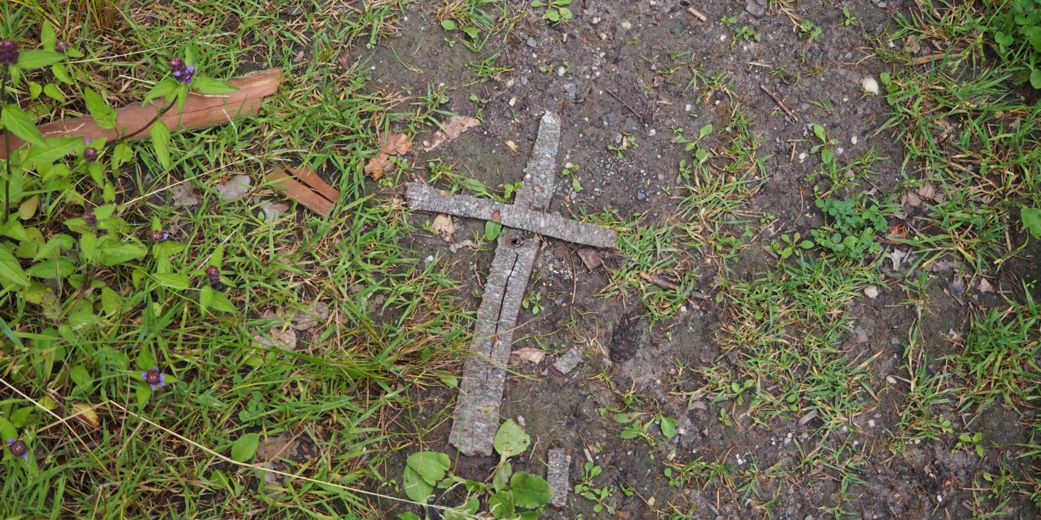 Auf Waldboden liegt ein aus Rinde geformtes Kreuz