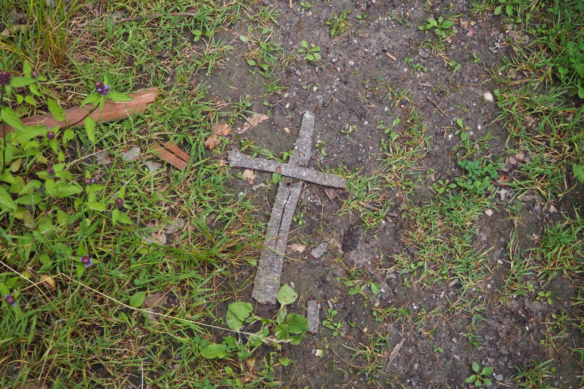 Auf Waldboden liegt ein aus Rinde geformtes Kreuz