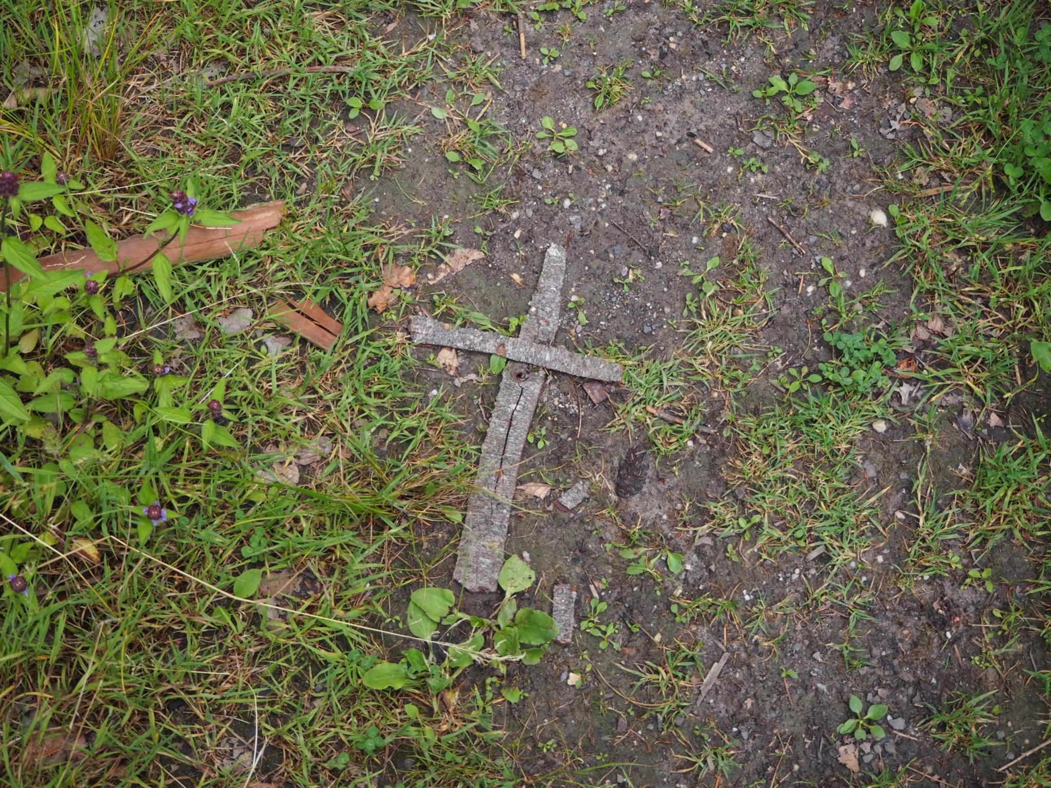 Auf Waldboden liegt ein aus Rinde geformtes Kreuz