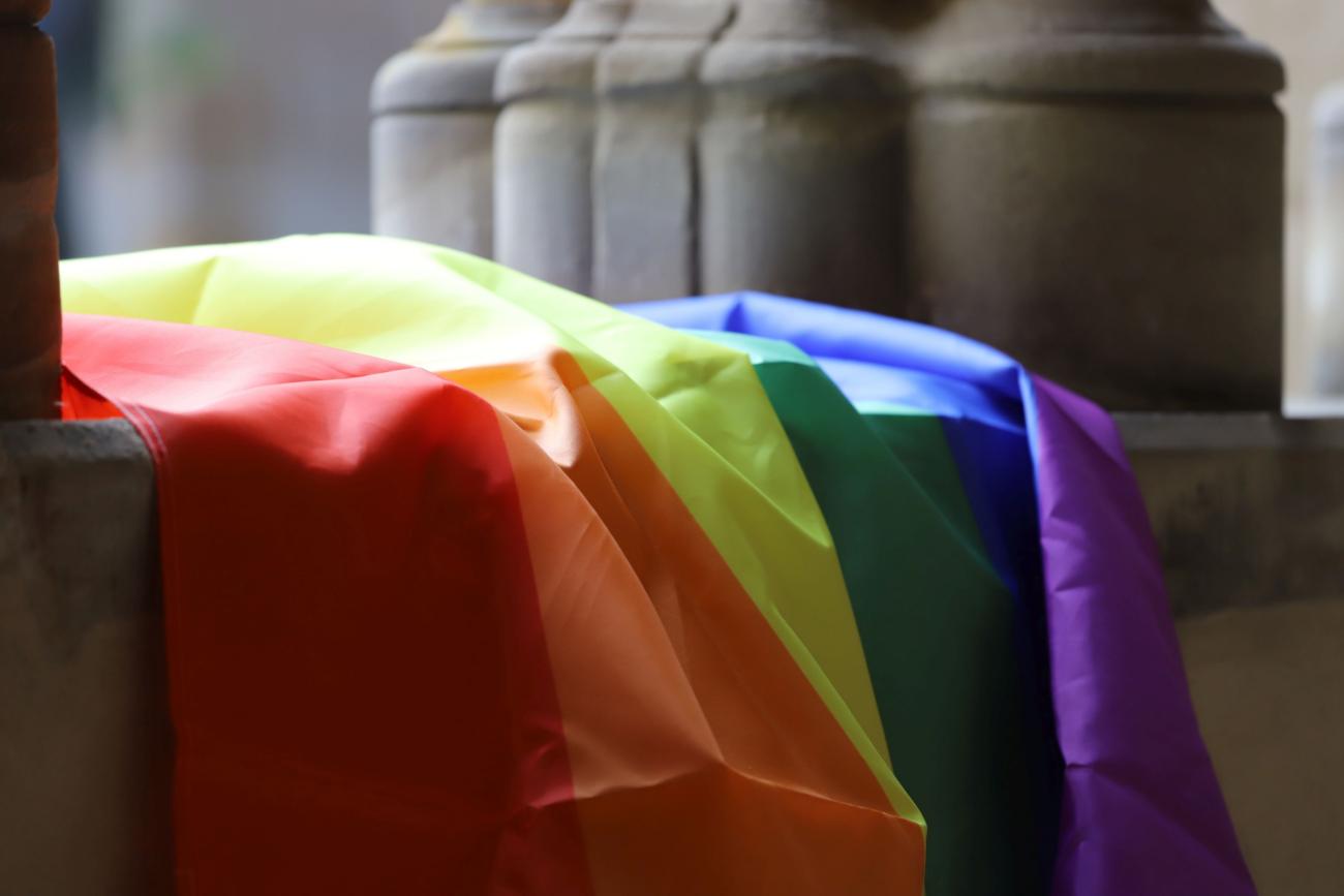 Regenbogenfahne (c) Inge Hülpes Eine Regenbogenfahne liegt auf einer Mauer