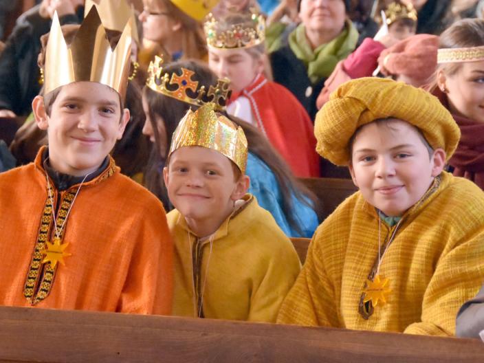 Drei Kinder als Könige verkleidet lächeln in die Kamera