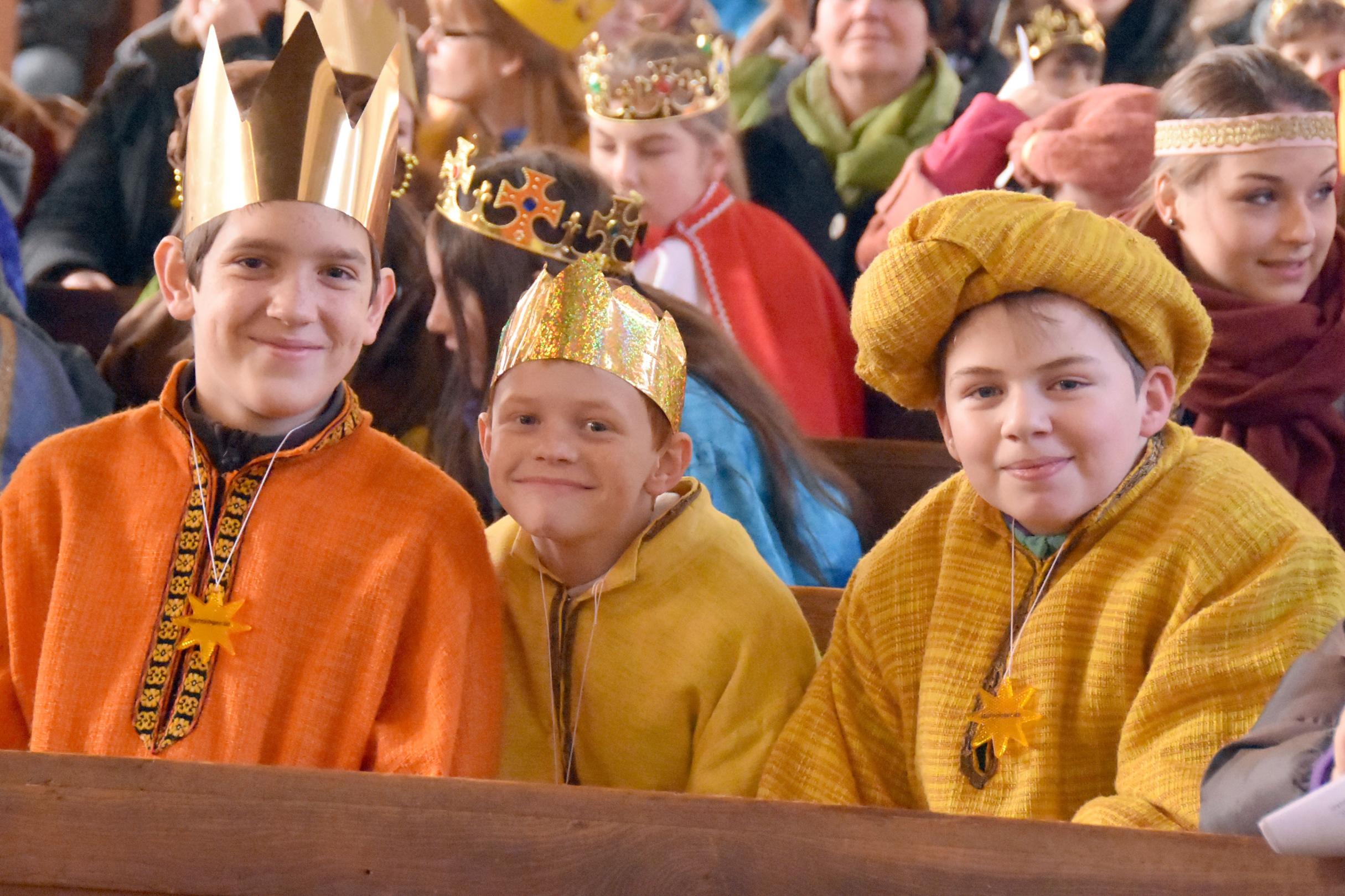 Drei Kinder als Könige verkleidet lächeln in die Kamera