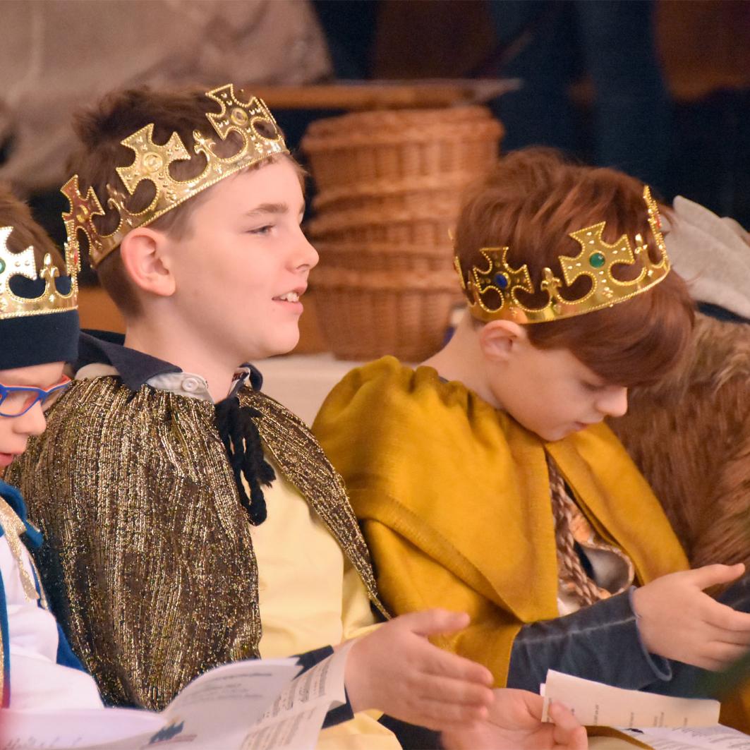 Kinder als Könige verkleidet sitzen in einer Kirchenbank