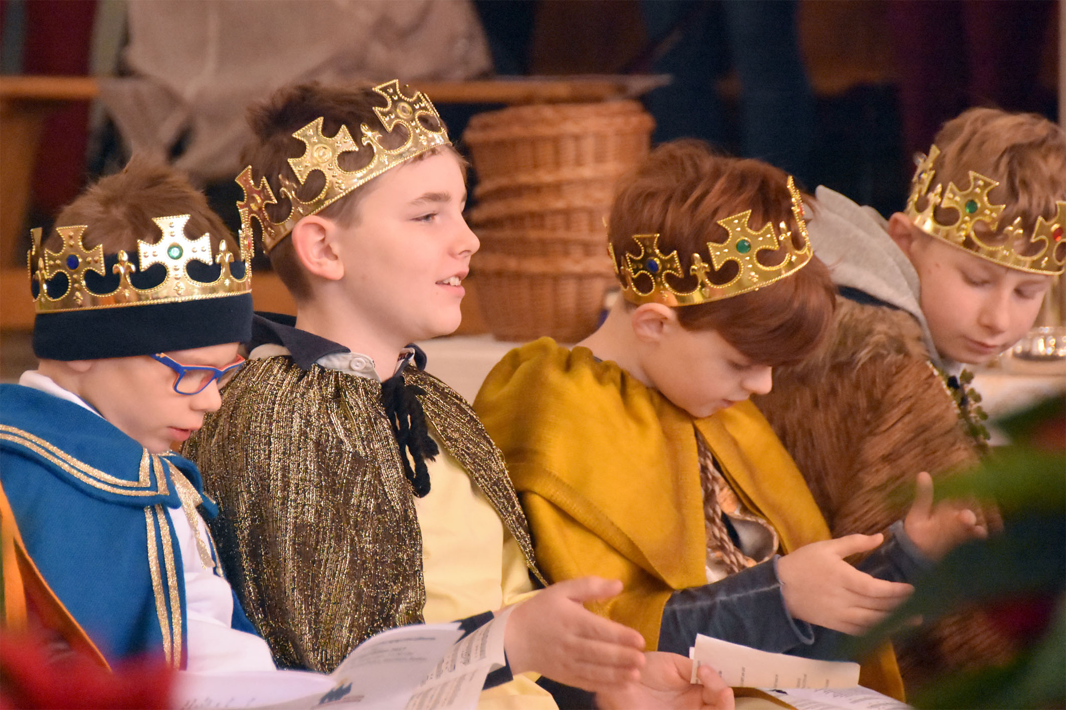 Kinder als Könige verkleidet sitzen in einer Kirchenbank