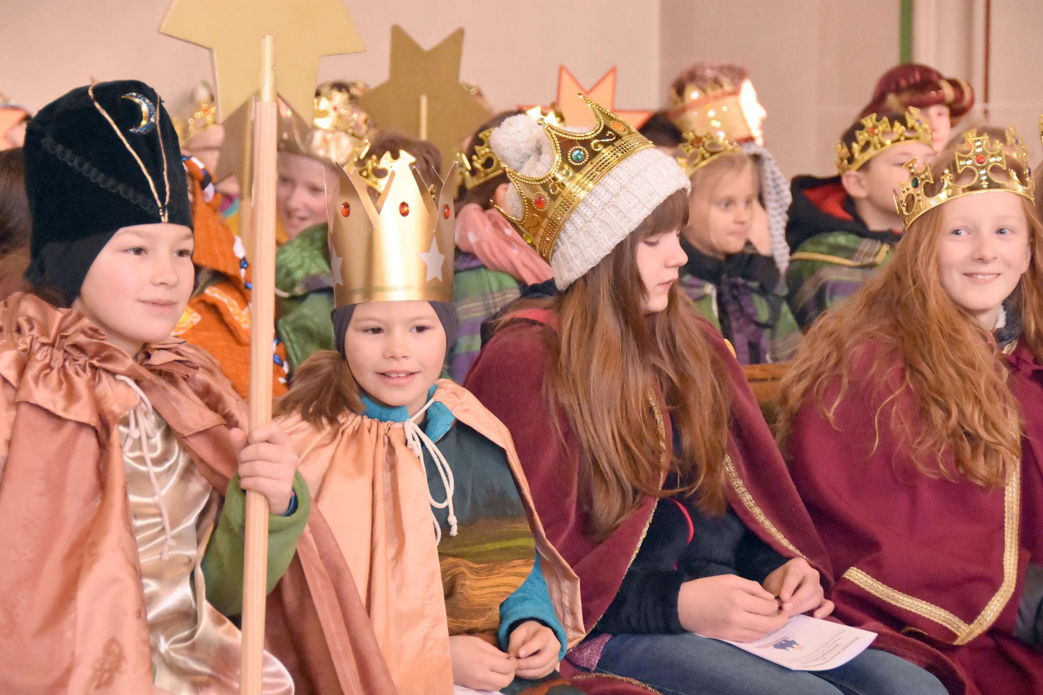 Kinder als Könige verkleidet sitzen in Gruppen zusammen in der Kirche